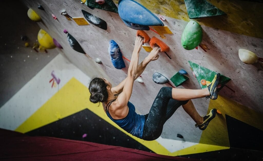 a woman bouldering in a climbing gym